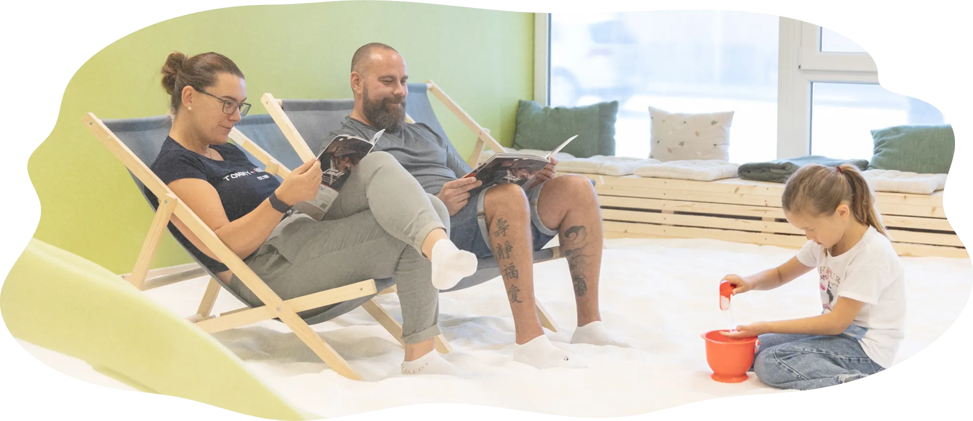 salzhof_bild_7 Erwachsene lesen entspannt in Liegestühlen, während ein Kind im Salz des SALZHOF spielt